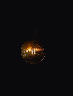 A flickering light bulb hanging from a ceiling in darkness.
