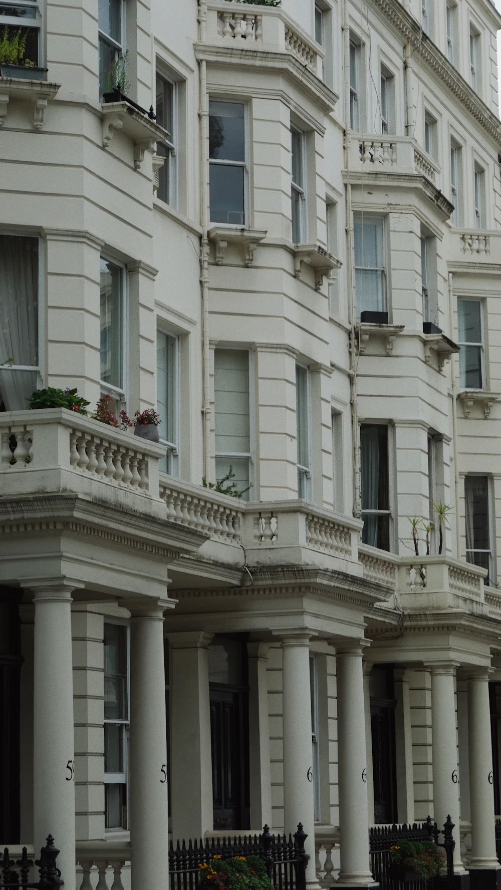 Stucco townhouse facade with bay windows and a stone balustrade