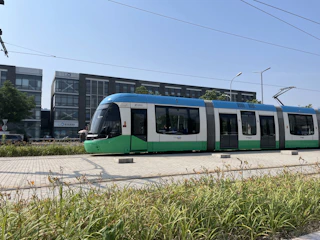 A sleek, modern tram gliding along polished steel tracks beneath a crisp blue sky, symbolizing precision and innovation.