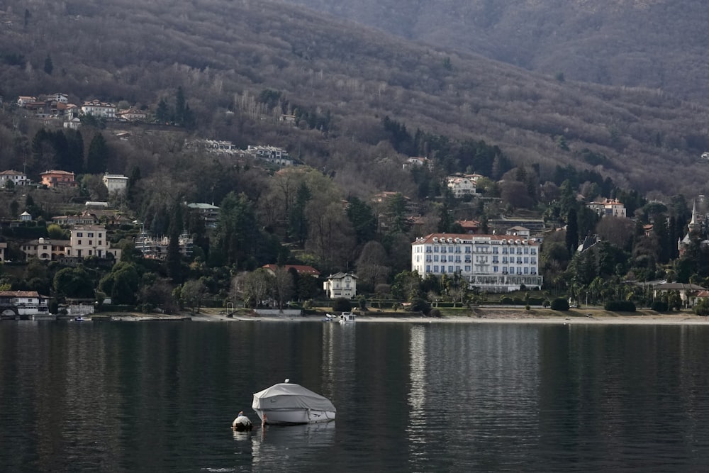 a boat floating on top of a lake next to a lush green hillside