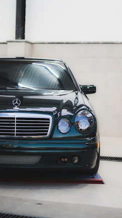Mercedes luxury car parked inside a sleek, brightly lit automotive workshop.