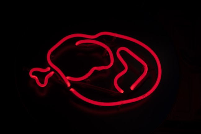 The vibrant exterior sign of Dynos Chicken Pomona glowing at dusk.