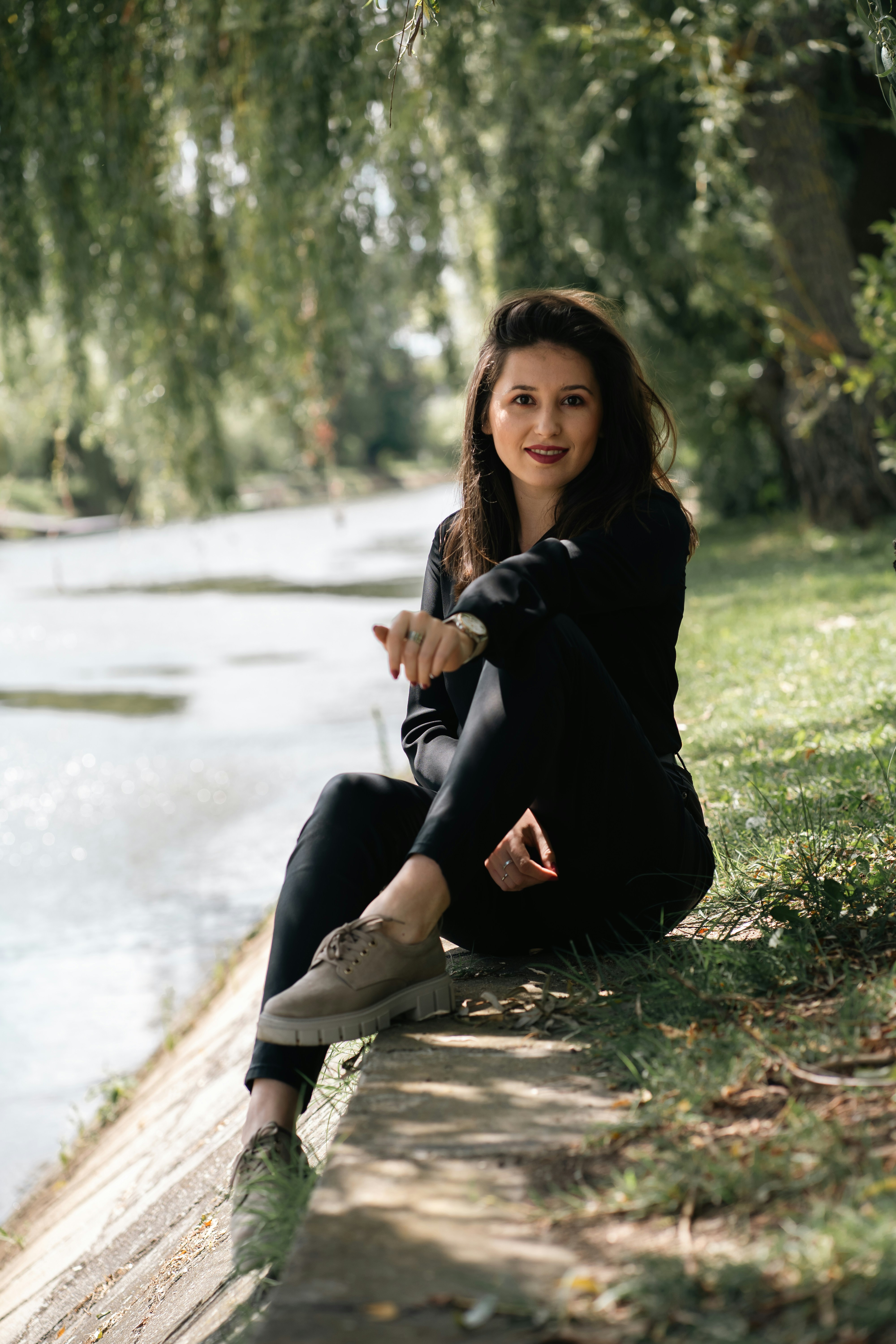 a woman is sitting on the bank of a river