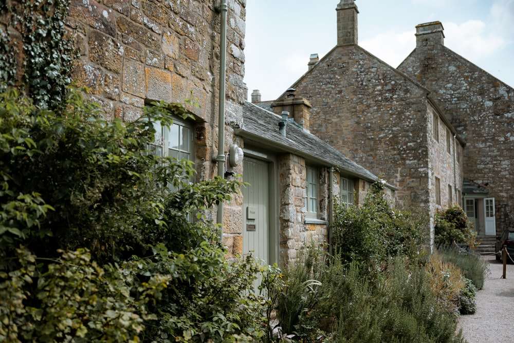 a stone building with a green door surrounded by greenery