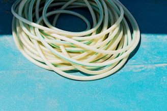 A close-up of a bright, flexible PVC garden hose coiled beside a watering can.