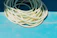 Close-up of a green expandable garden hose coiled neatly on a sunny patio.