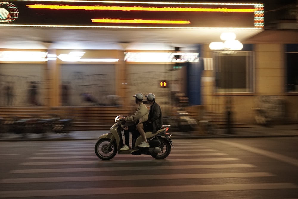 a man and a woman riding a motorcycle down a street