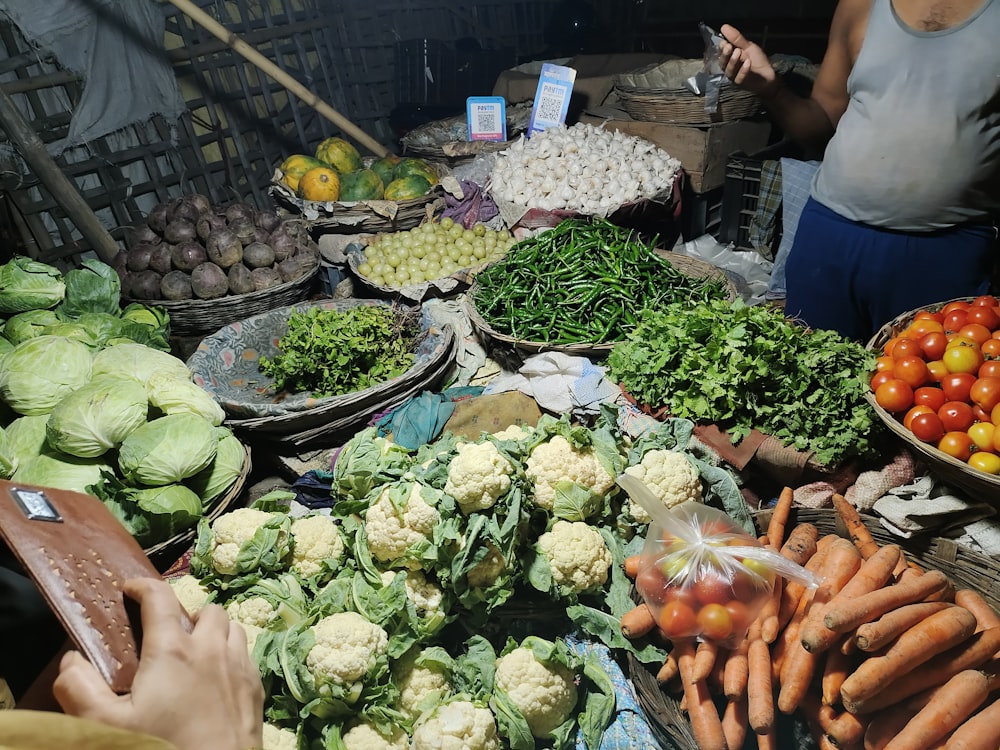 a woman standing in front of a table filled with lots of vegetables