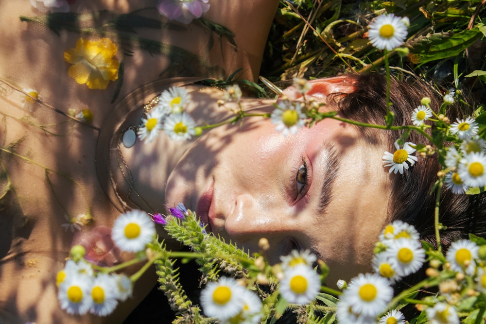 a woman laying in a field of daisies