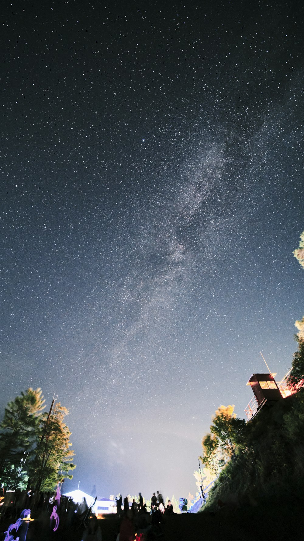 a group of people standing on top of a hill under a night sky