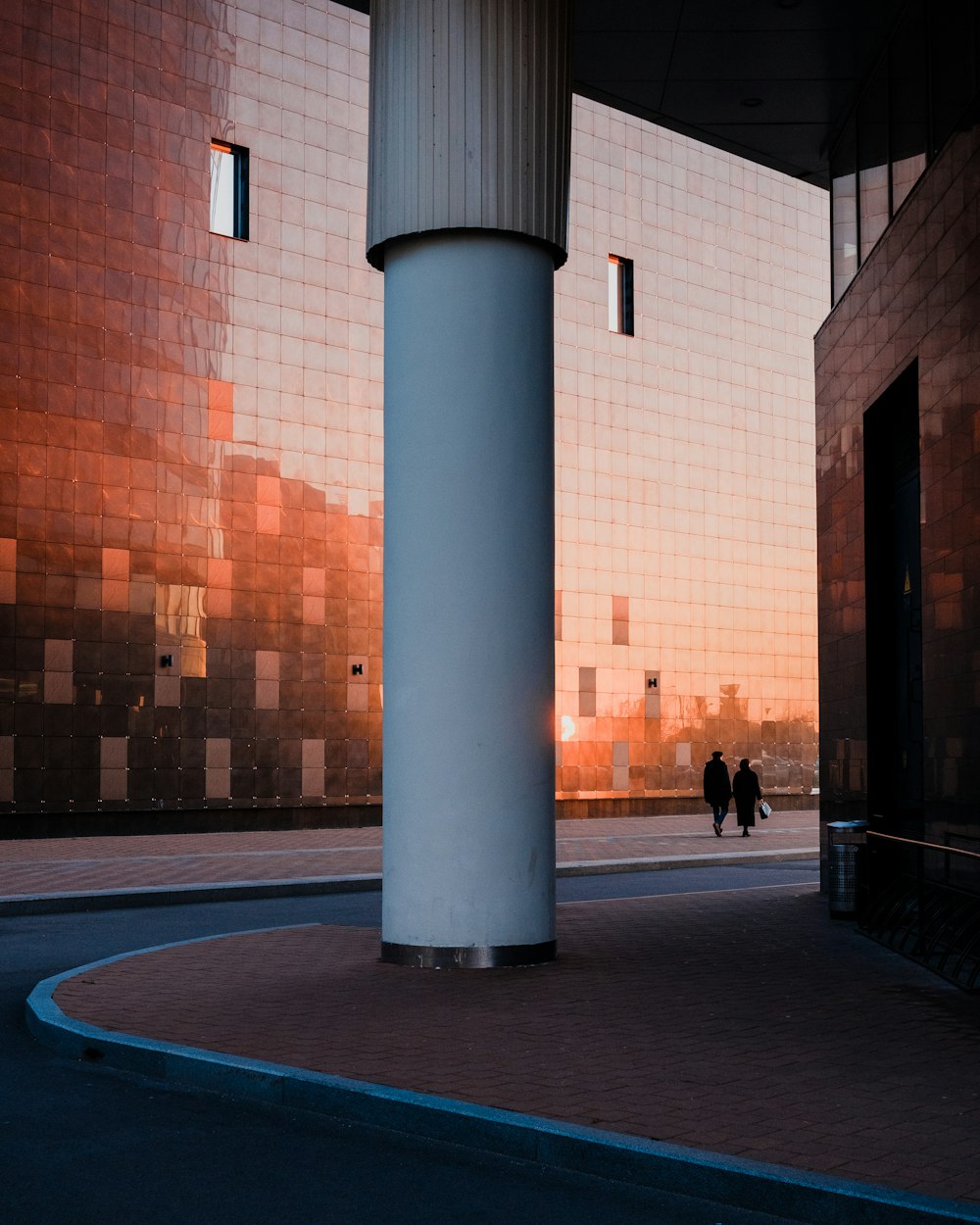 a couple of people walking down a street next to a tall building