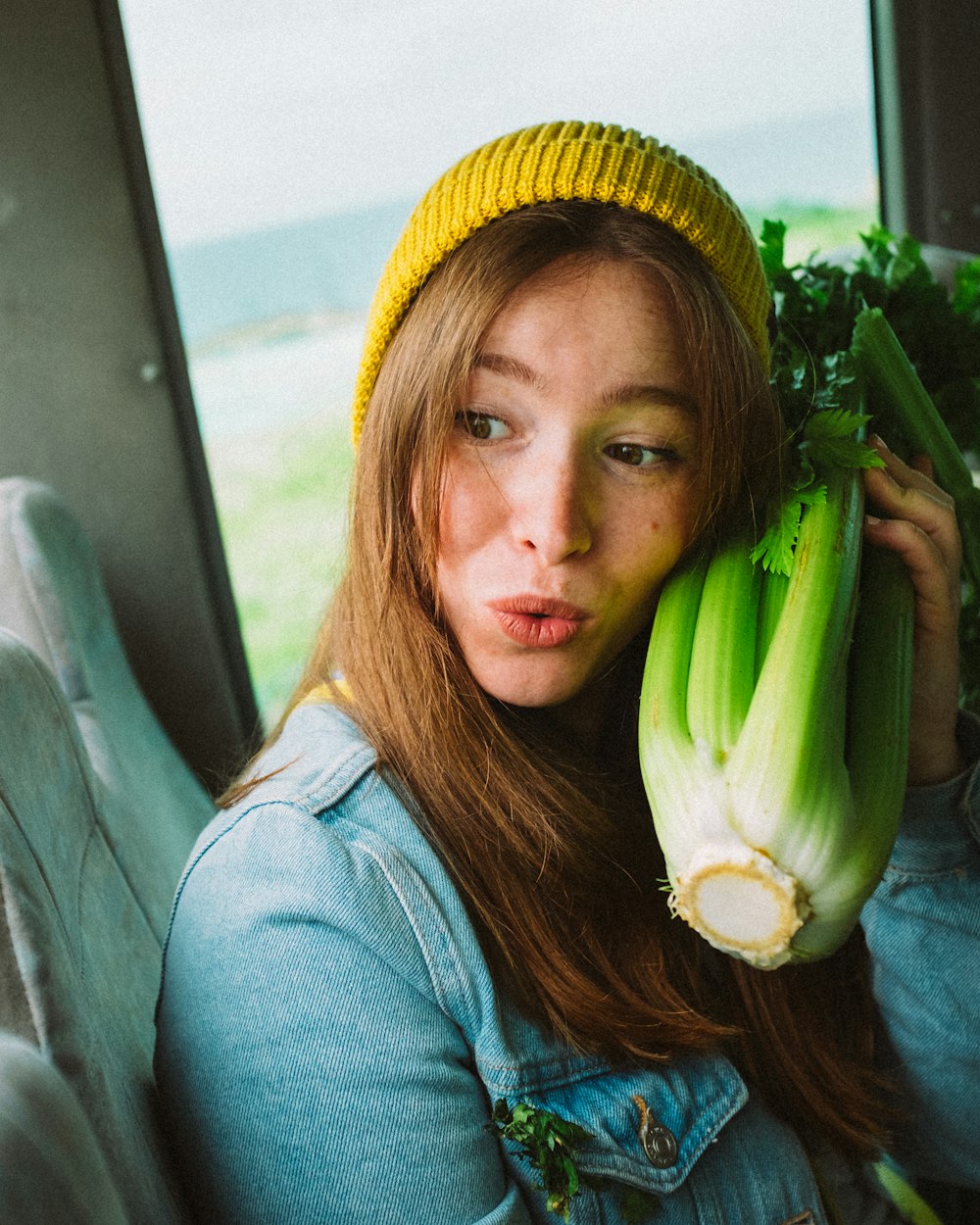 a woman holding a bunch of green vegetables