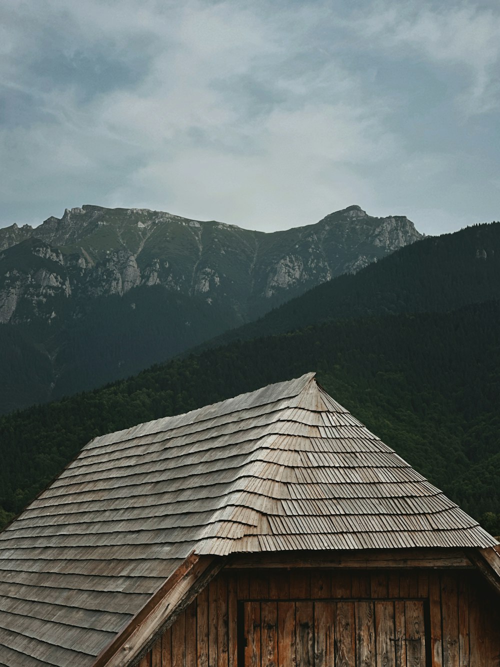 a wooden building with mountains in the background