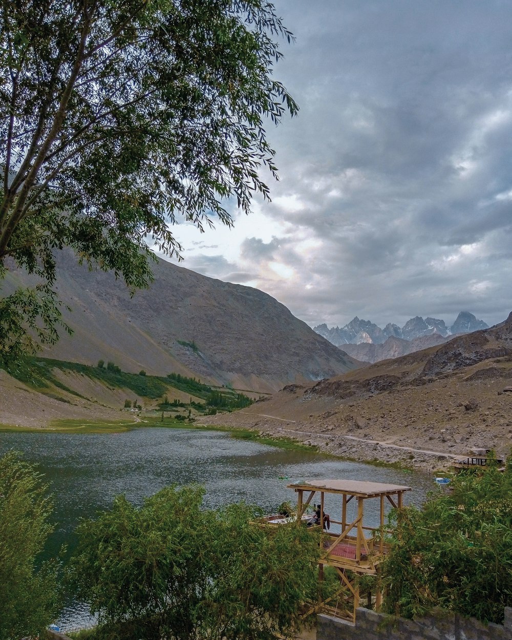 a lake surrounded by mountains under a cloudy sky