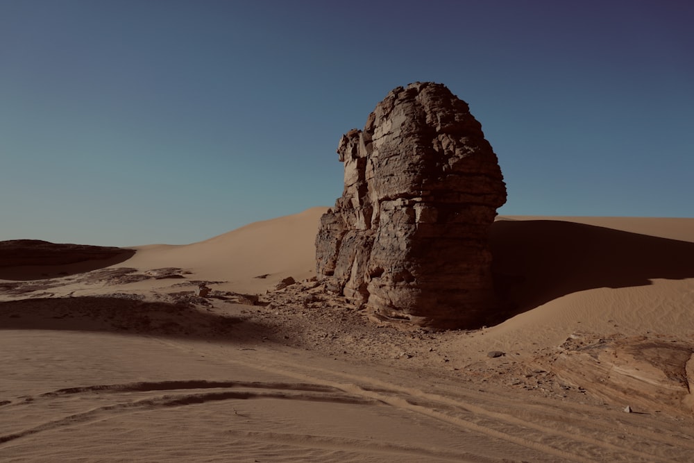 a large rock in the middle of a desert