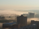 A wide panoramic shot of a misty urban skyline at dawn, soft light bathing the buildings.