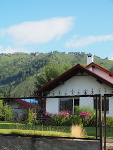 A charming house with a garden and a red roof under a bright blue sky.