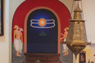 A colorful canvas wall painting featuring traditional Indian motifs in warm golden and deep red hues.