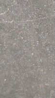 A concrete surface with a rough texture, featuring small pebbles and stones embedded within it. The surface has a gray color overall with specks of brown, beige, and white.