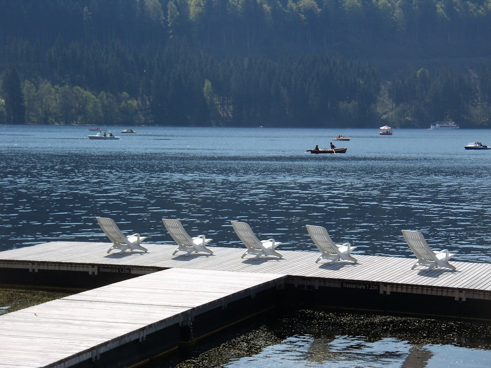 a dock with chairs and a row of boats in the water