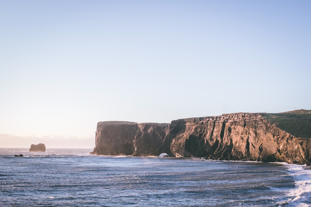 a large body of water next to a rocky cliff