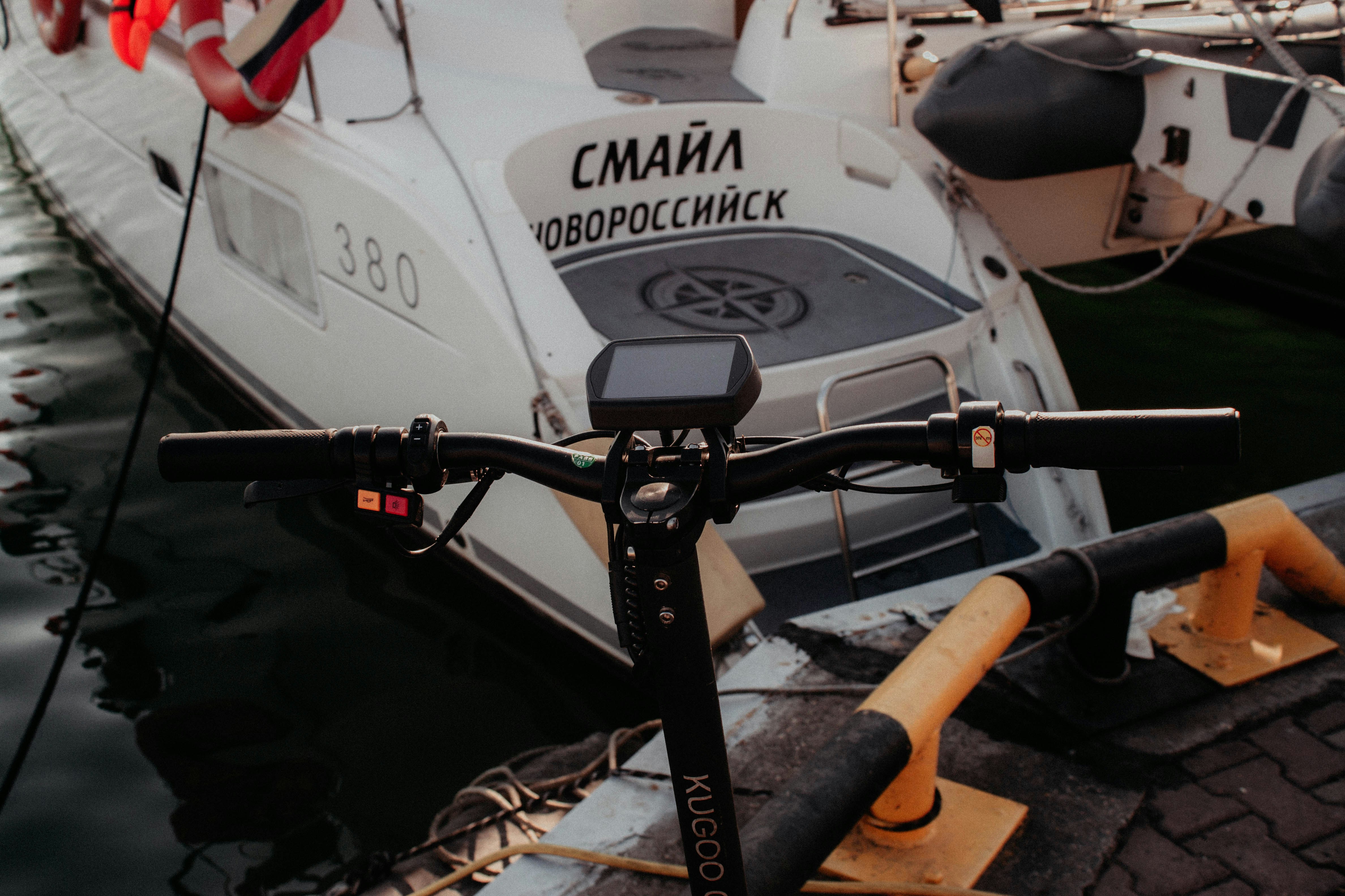 a close up of a bike parked next to a boat, scooter at the seaport next to the yacht