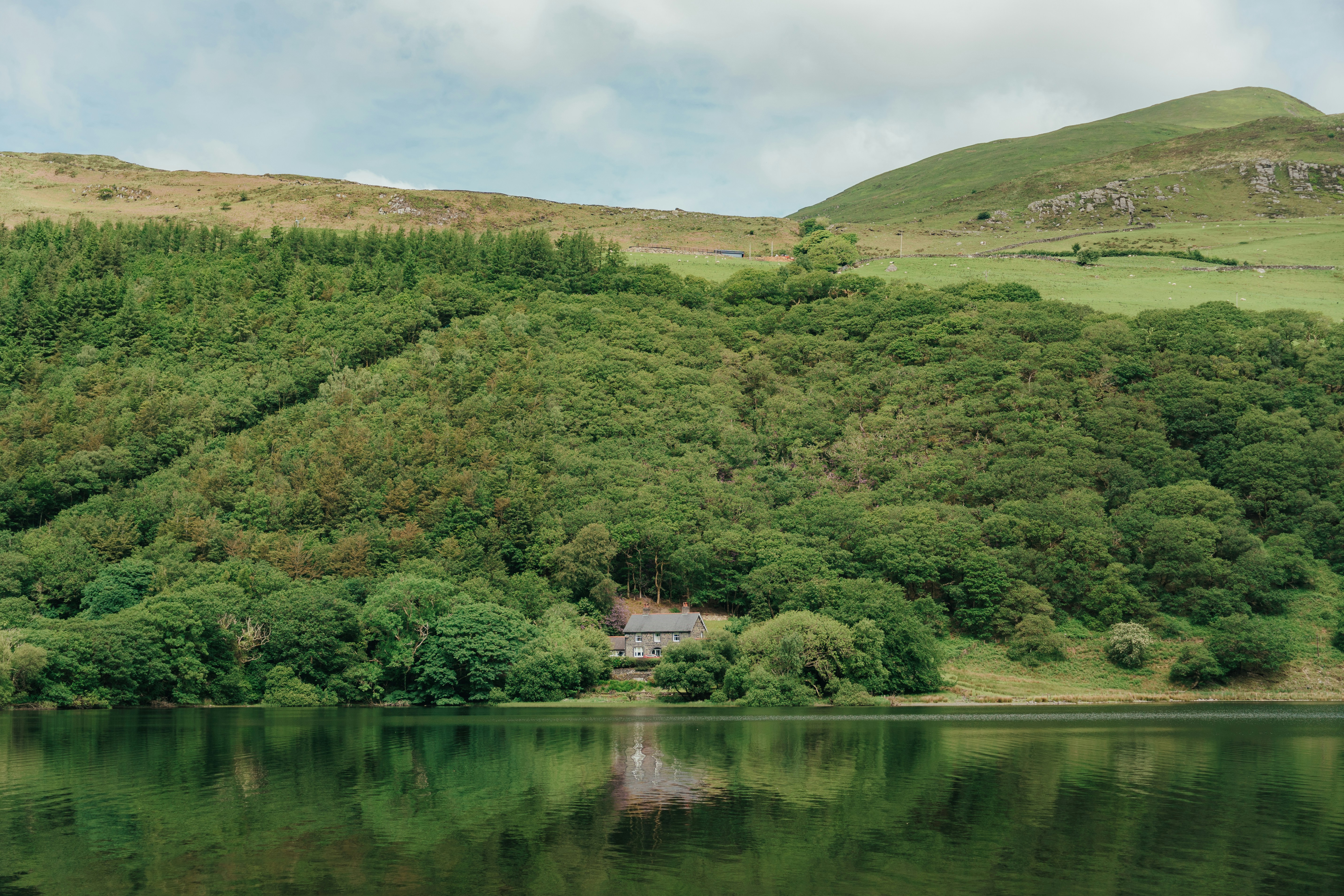 a house on the side of a hill next to a body of water