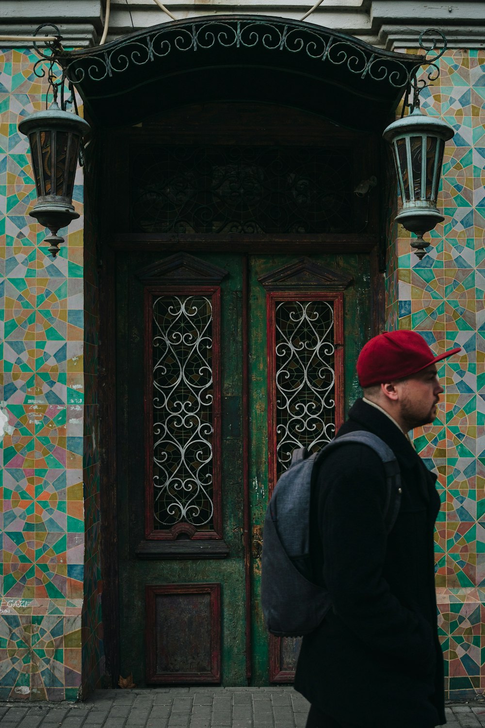 a man in a red hat walking past a green door