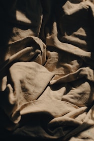 Artistic shot of folded neutral-toned fabrics with subtle golden threads, highlighting texture and quality.