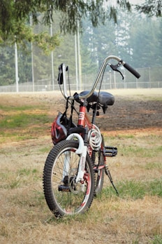 A colorful child safety helmet hanging on a bike handlebar in a sunny park.
