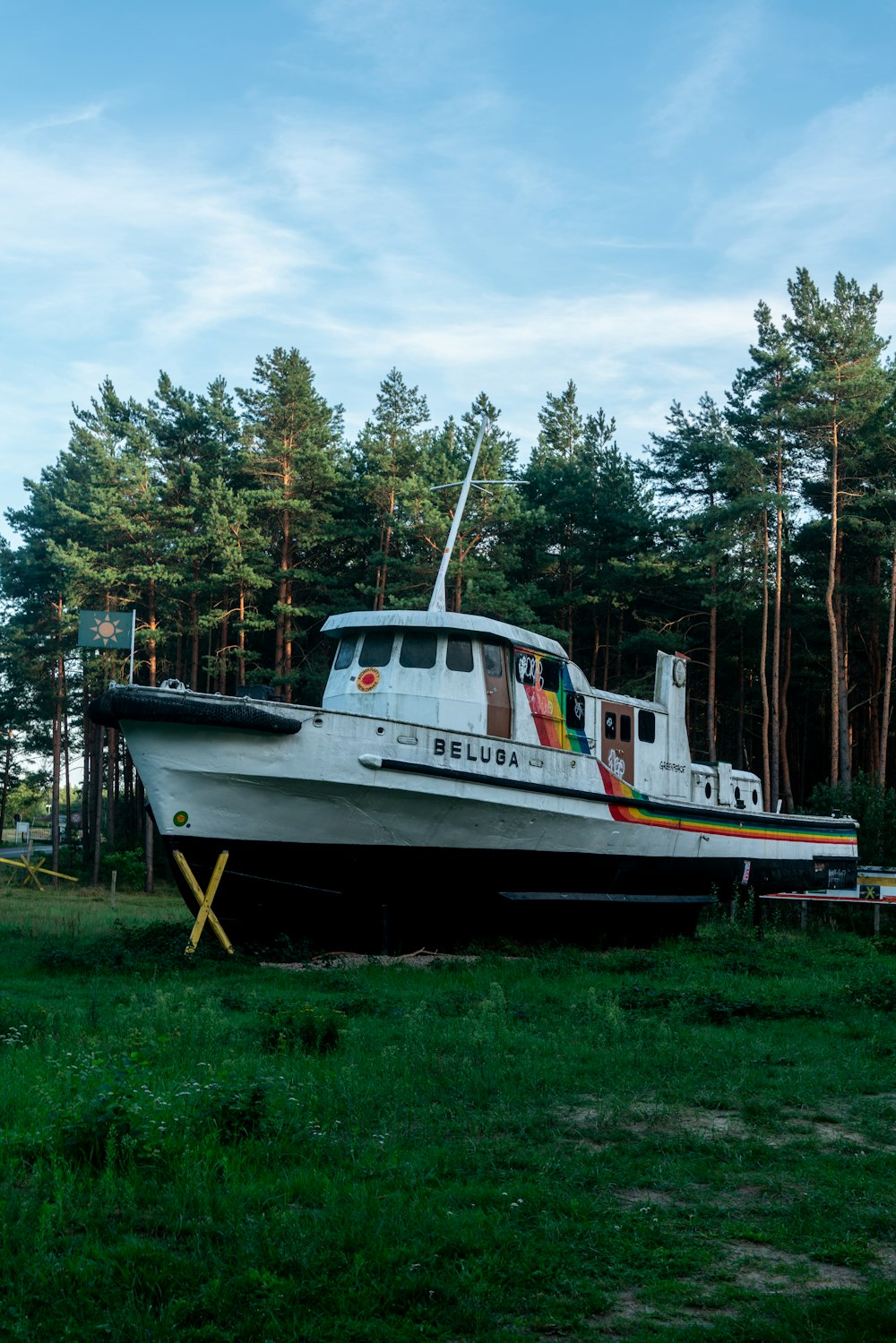 a white boat sitting on top of a lush green field