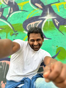 A casual streetwear look featuring a girl wearing a colorful camisita chica, smiling against a graffiti wall.