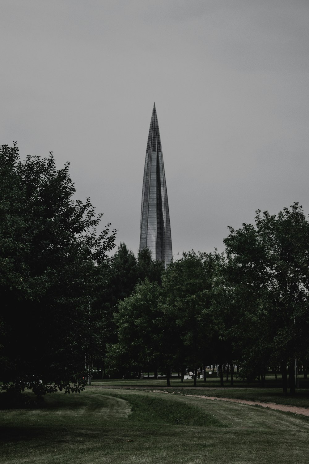 a very tall building towering over a lush green park
