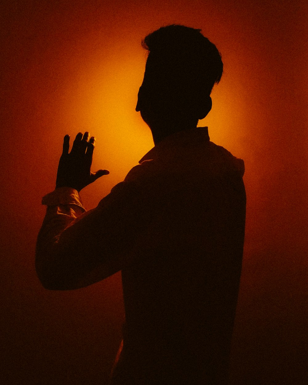 a silhouette of a man holding his hands up in the air