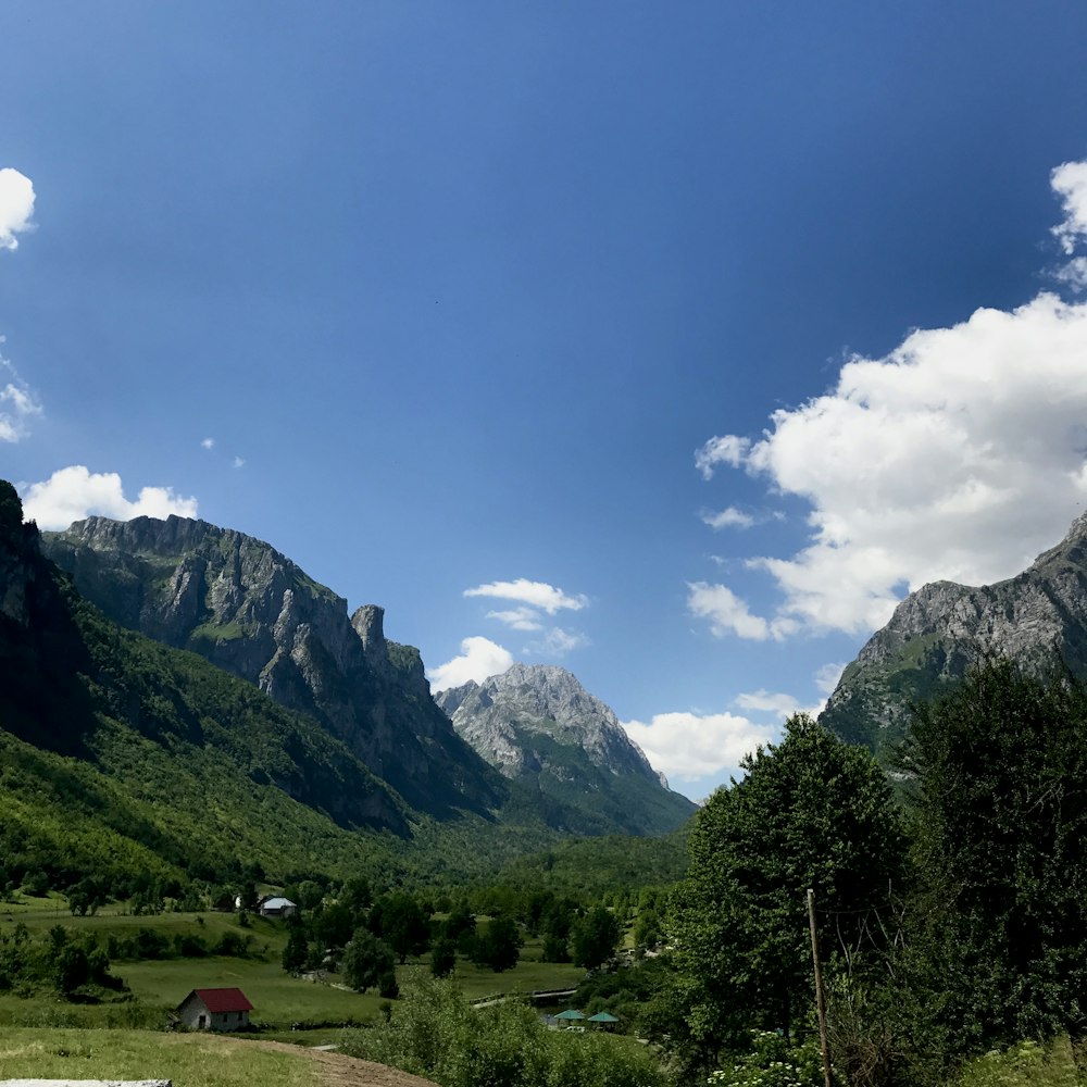 a scenic view of a mountain range with a house in the foreground