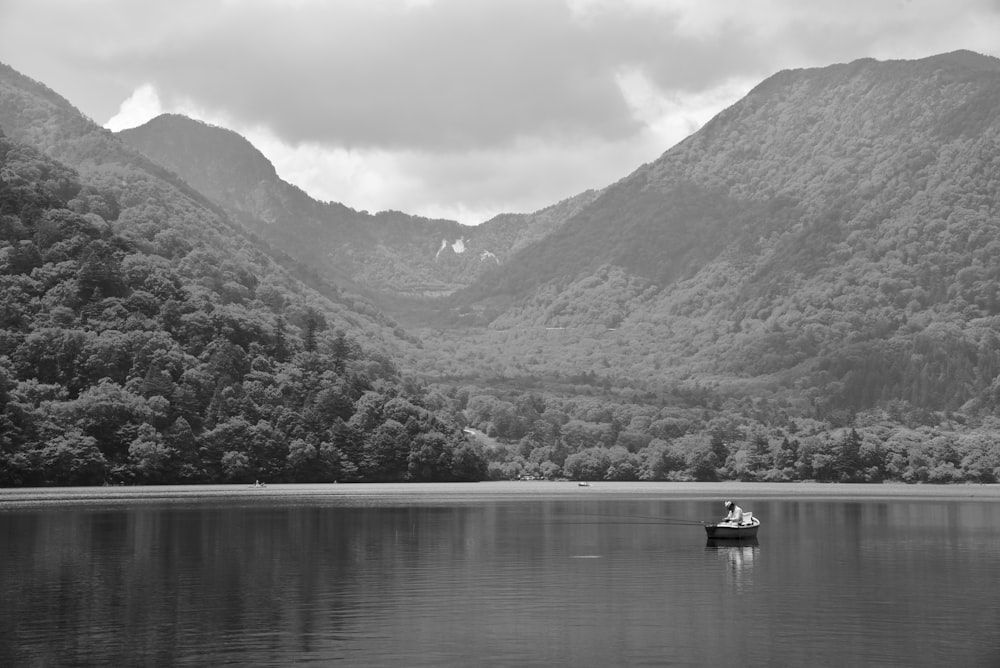 a boat floating on top of a lake surrounded by mountains