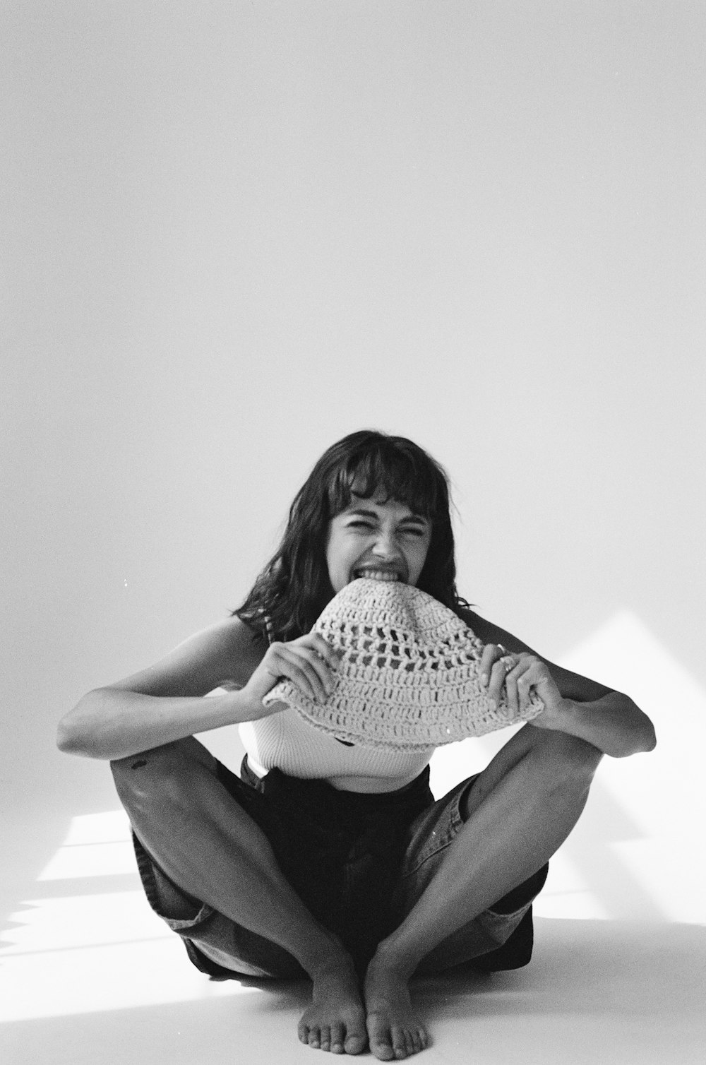 a woman sitting on the ground holding a hat