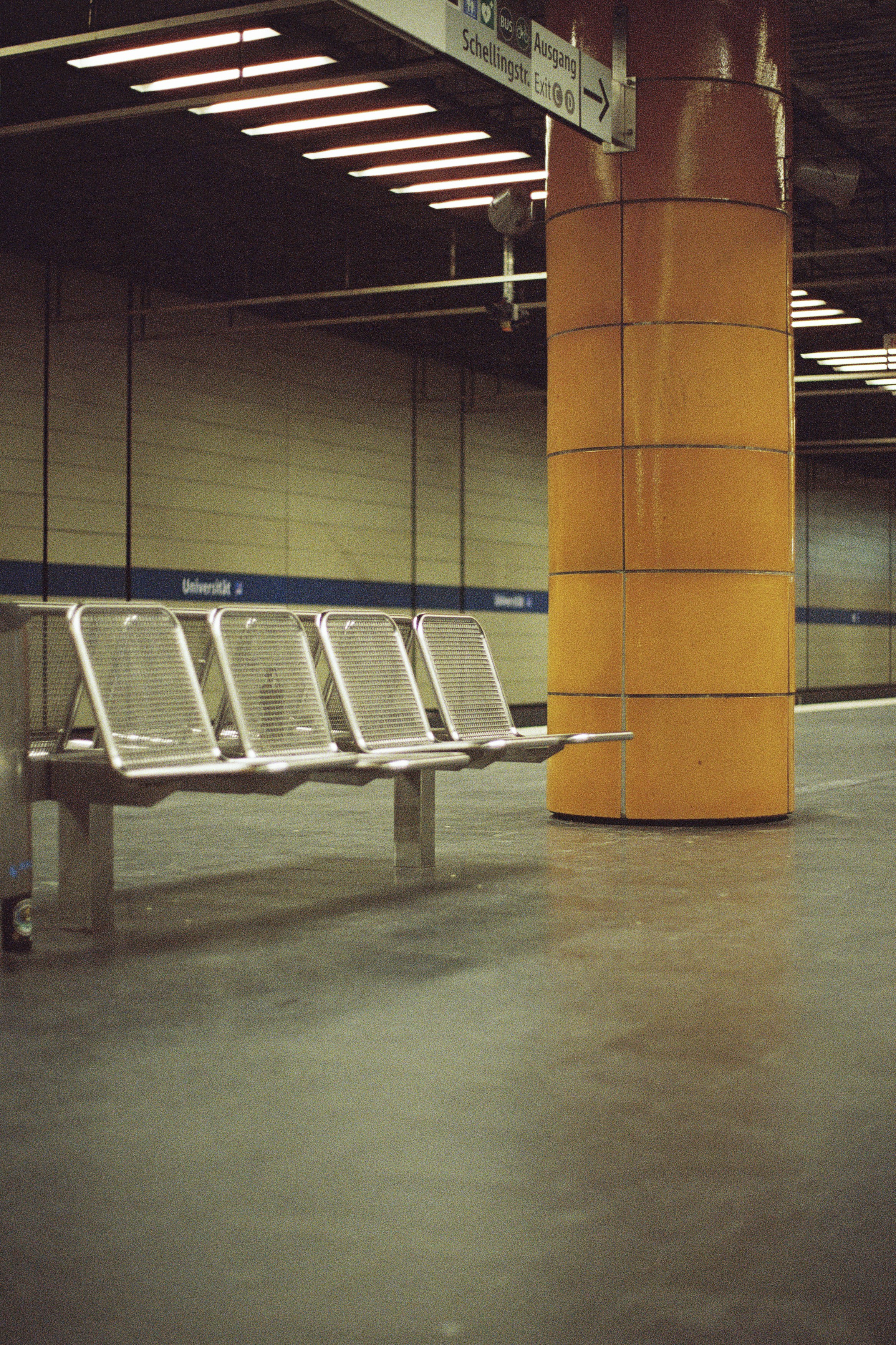 a row of metal benches sitting next to a yellow pillar