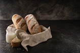 Artisanal bread and preserves styled on a crisp parchment background with matte forest green accents.