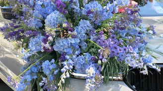 Close-up of delicate floral arrangements being carefully placed on a car’s hood.