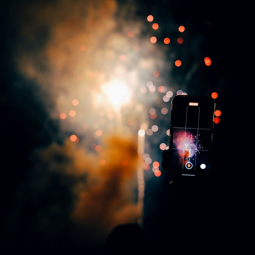 une personne prenant une photo de feux d’artifice avec un téléphone cellulaire