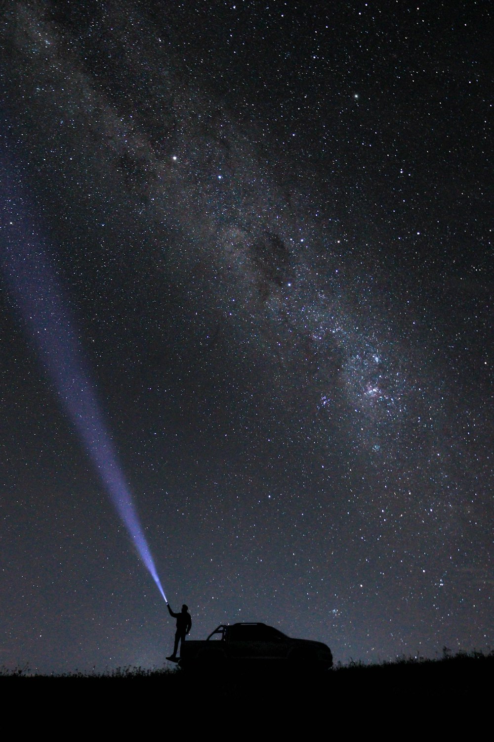 a person standing next to a car under a night sky