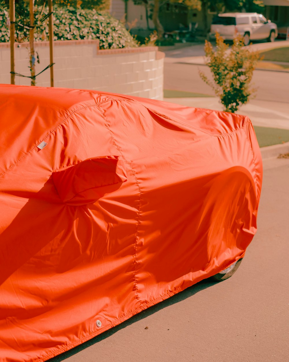 a car covered in an orange sheet on the side of the road
