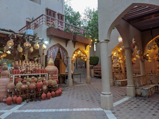 A sunlit artisan tent with handcrafted pottery displayed on wooden tables under soft green canopies.