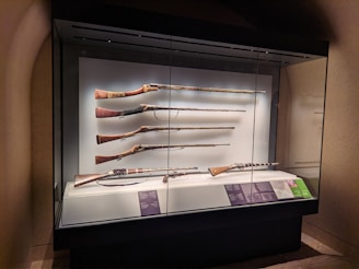 A collection of historical firearms displayed carefully in a wooden cabinet.