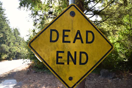 a yellow dead end sign sitting on the side of a road