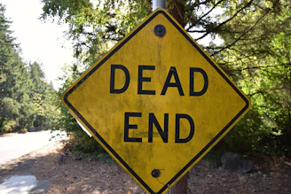 a yellow dead end sign sitting on the side of a road