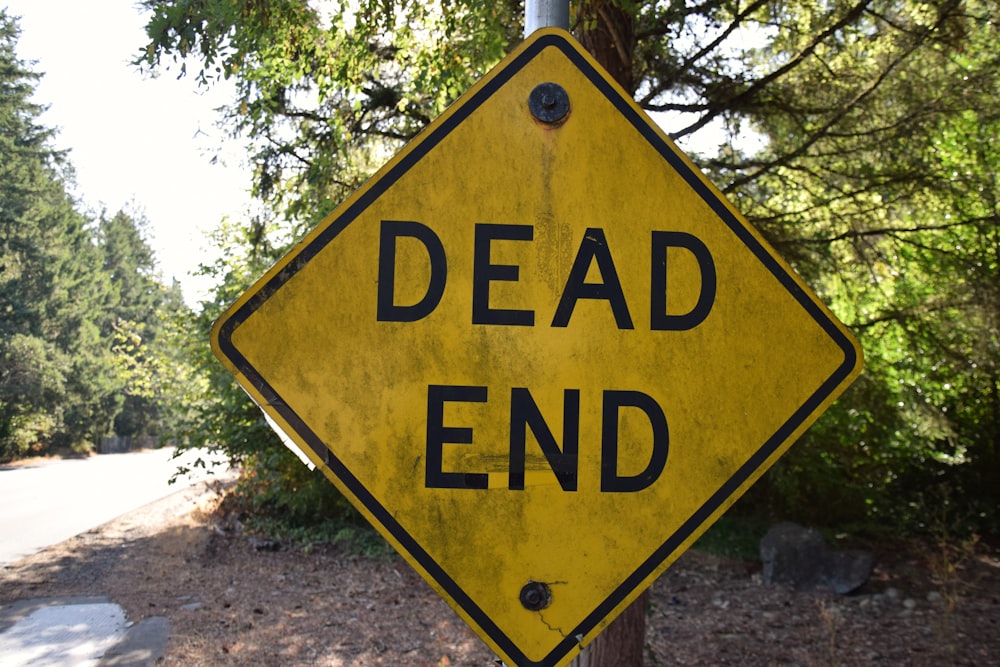 a yellow dead end sign sitting on the side of a road