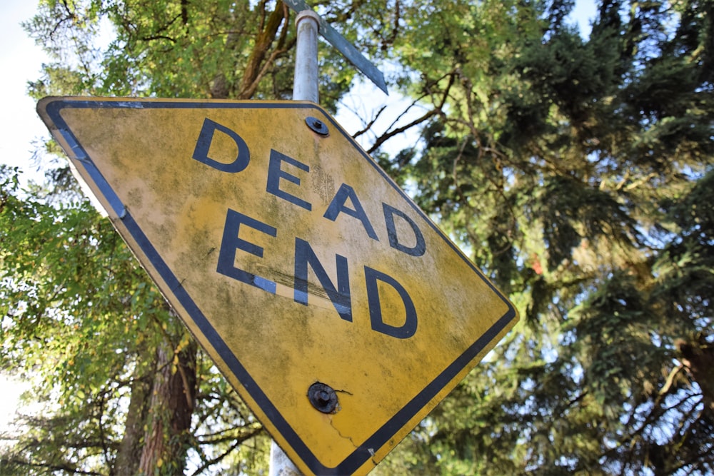 a yellow dead end sign hanging from a metal pole