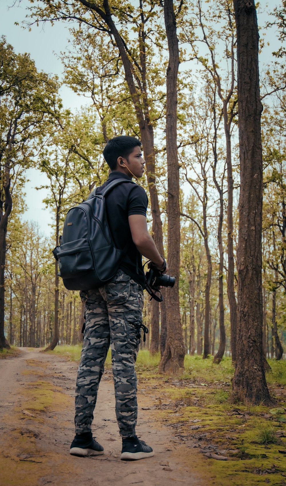 a man standing on a dirt road with a camera